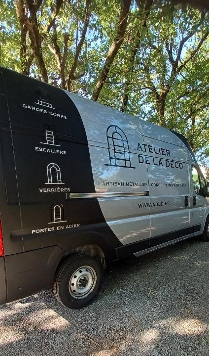 Fourgon gris de l’Atelier de la Déco, floqué du logo, de l’adresse adld.fr et des quatre spécialités de l’atelier : gardes-corps, escaliers, verrières, portes en acier.
