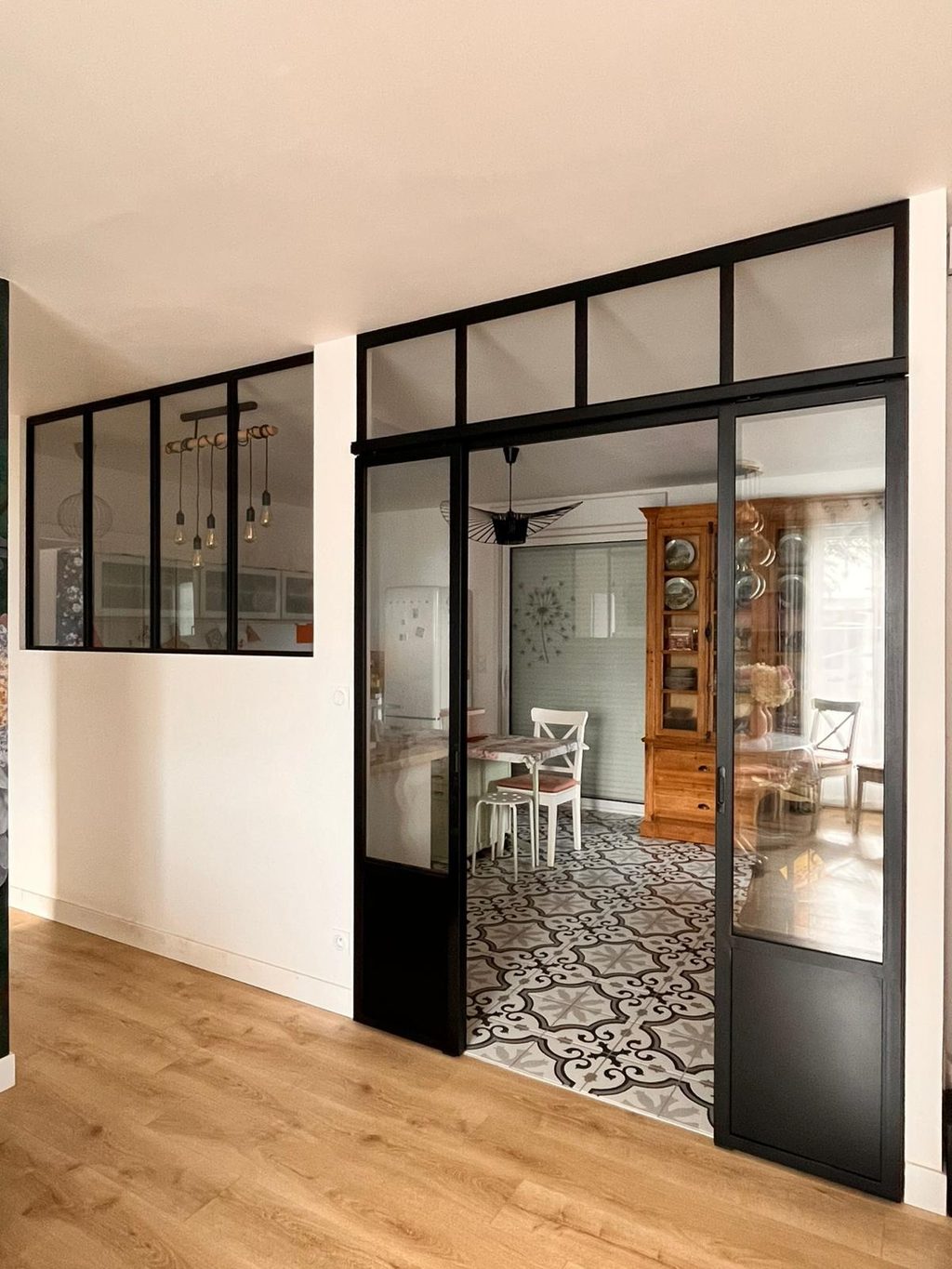 Porte coulissante vitrée en acier noir ouverte sur une salle à manger.