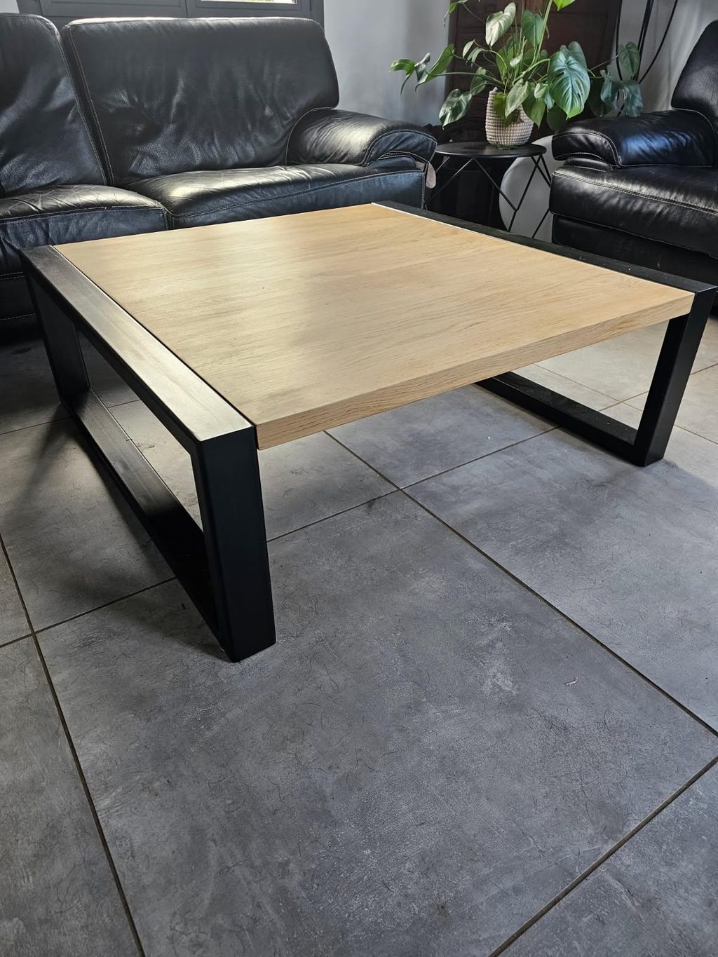 Table basse à piètement d’acier noir et plateau de bois clair, dans un séjour.