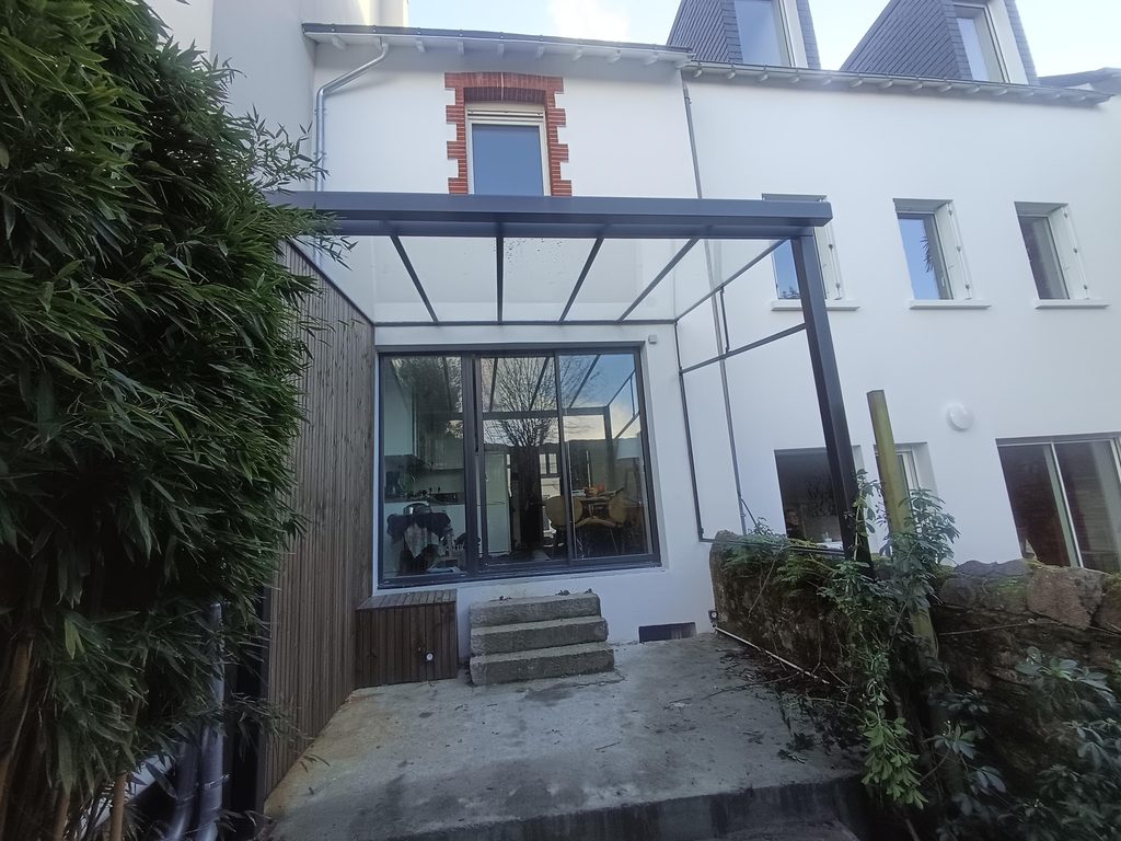 Détail d’une véranda en acier : la jonction du toit vitré et de la façade.