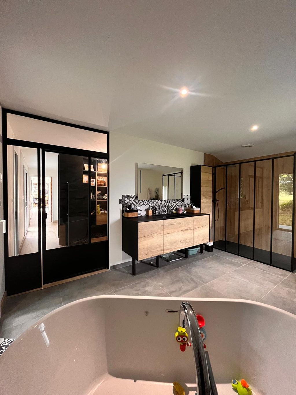 Paroi de douche en acier noir et verrière d’atelier dans une salle de bains.